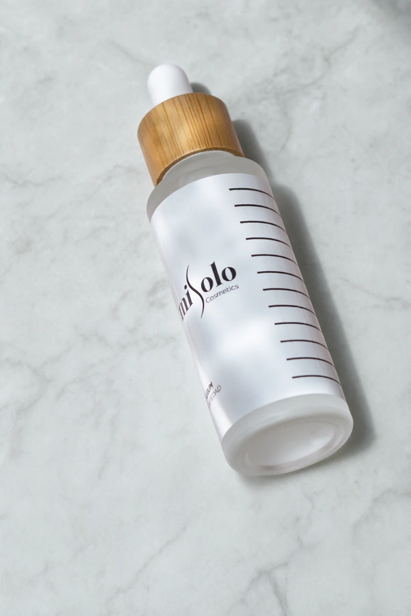 White serum bottle with a bamboo cap — Marble surface AI edit